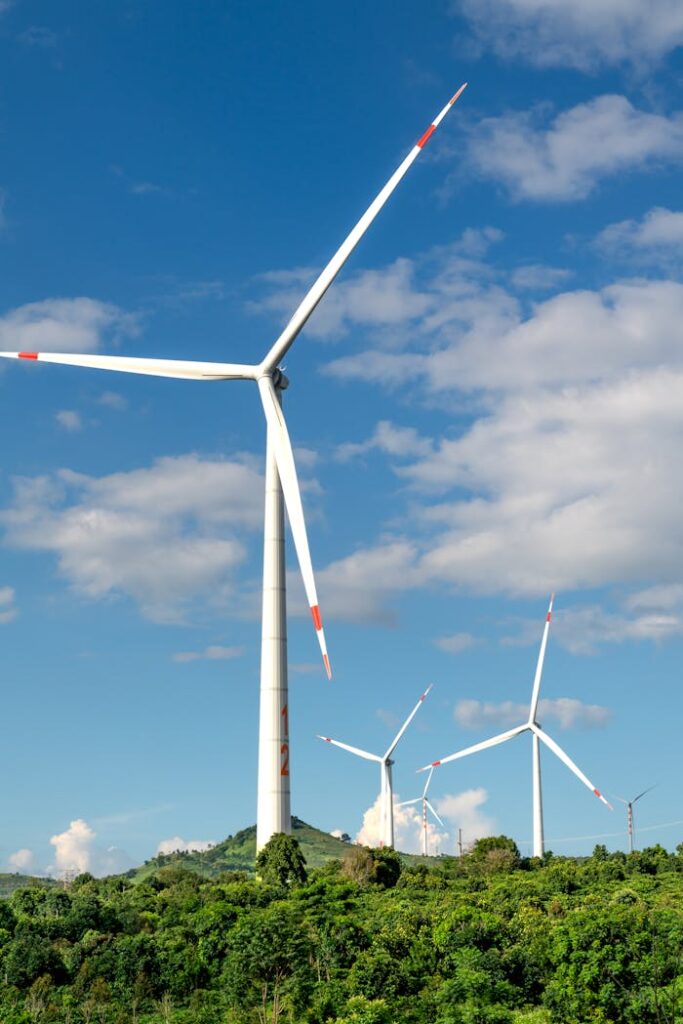 pexels photo 14024418 Wind turbines generating renewable energy on a lush green hilltop under a clear blue sky.