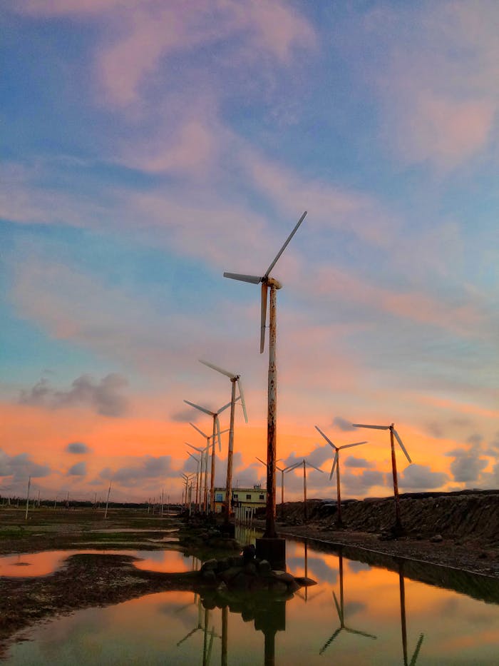 Beautiful view of wind turbines reflecting in water during a stunning sunset with vibrant skies.